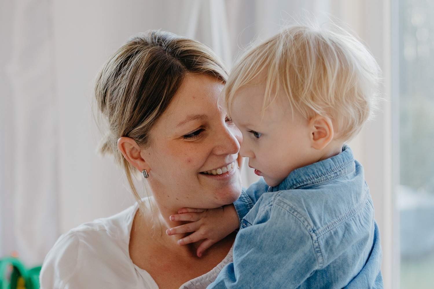 Porträtaufnahme von Mutter mit Sohn, schaut Kind an und lacht