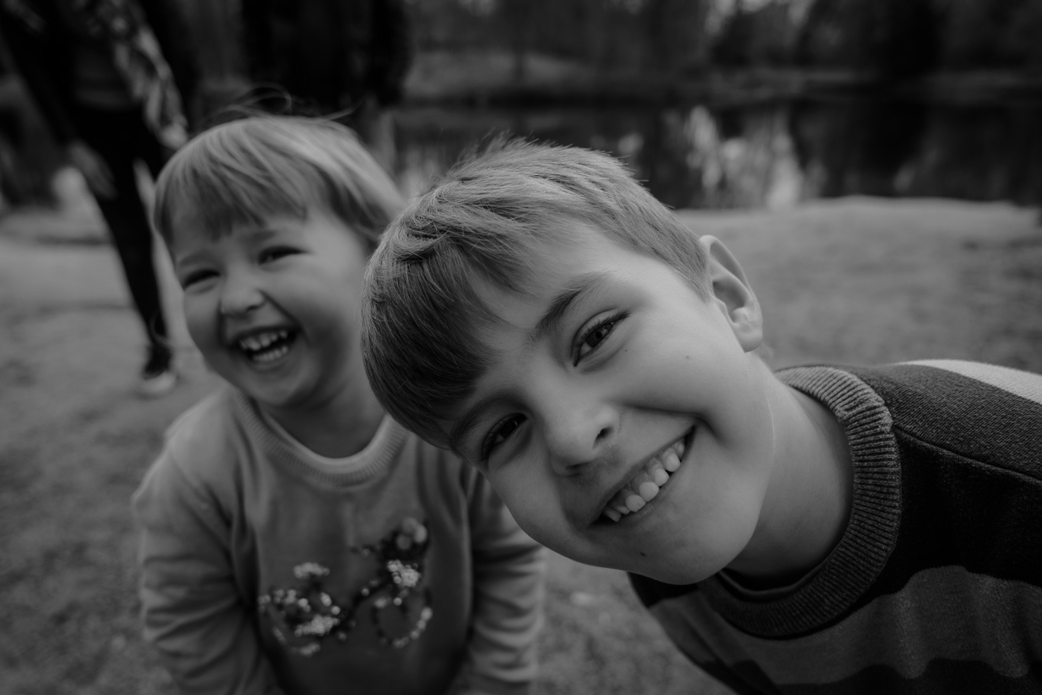 Schwarz-Weiss Familienfoto, kleines Mädchen und junge schauen lachend in die Kamera