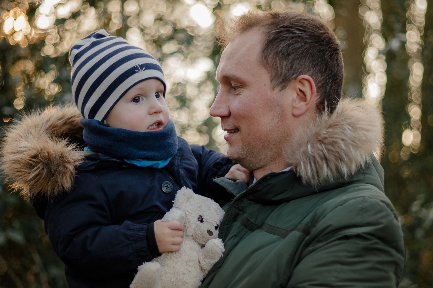 Portätaufnahme von Vater mit Sohn auf Arm, im Sonnenuntergang