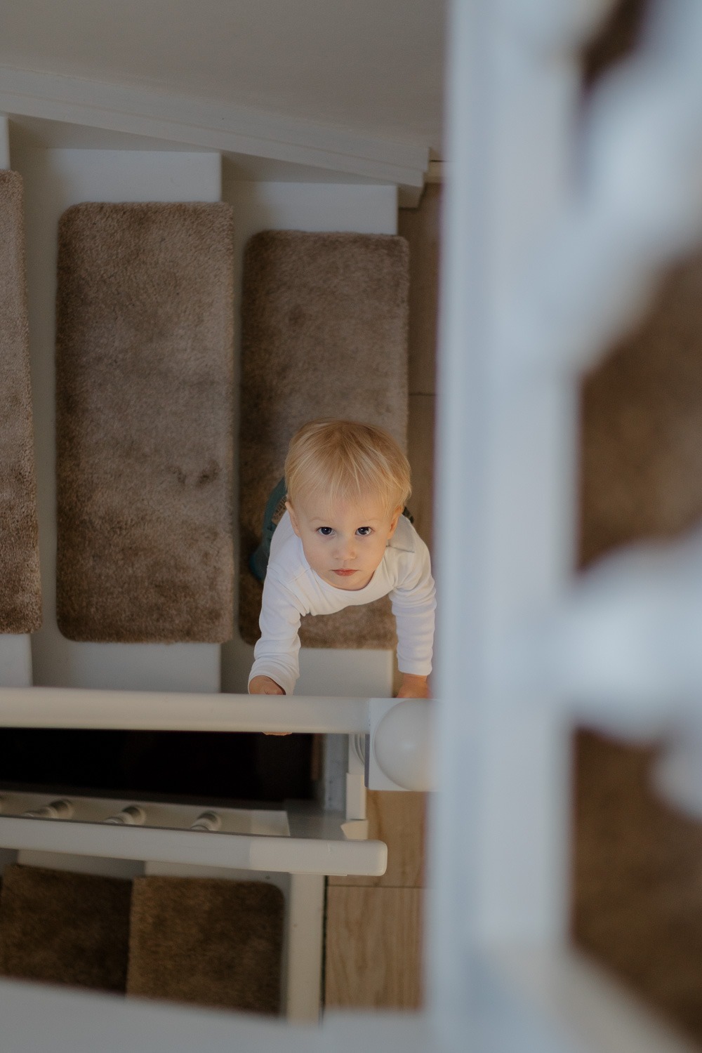 Porträtaufnahme von Kleinkind, von oben herab im Treppenhaus, Kind schaut nach oben in die Kamera