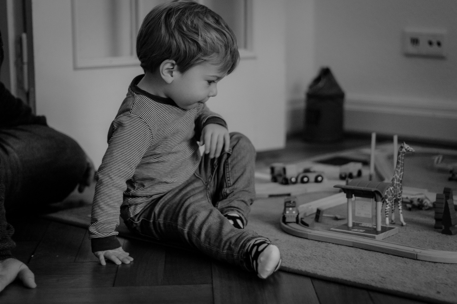 Schwarz-Weiss Aufnahme, Homestory, Junge mit Eisenbahn in Kinderzimmer spielend