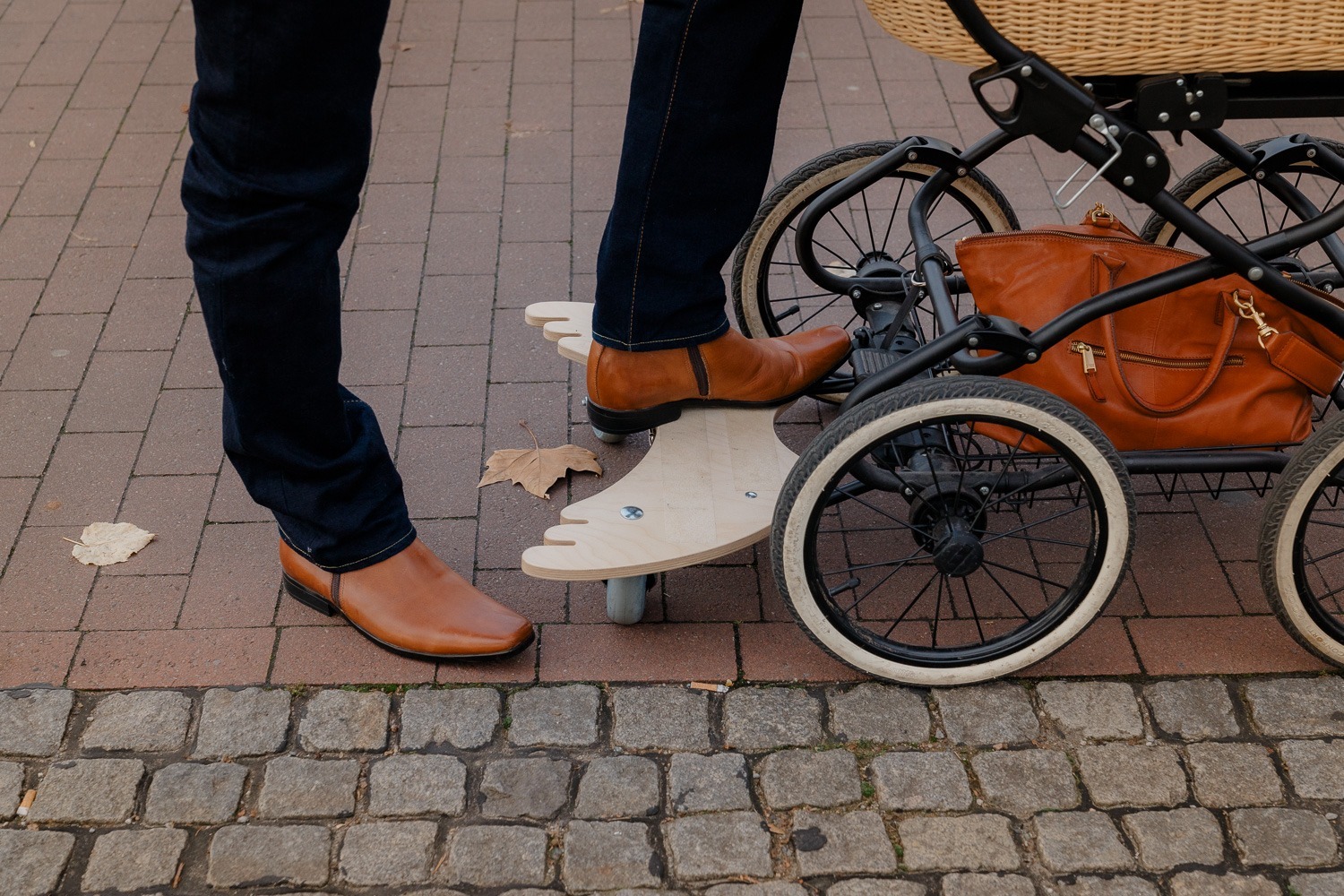 Detailaufnahme von Mann mit braunen Lederschuhen, der Kinderwagen schiebt