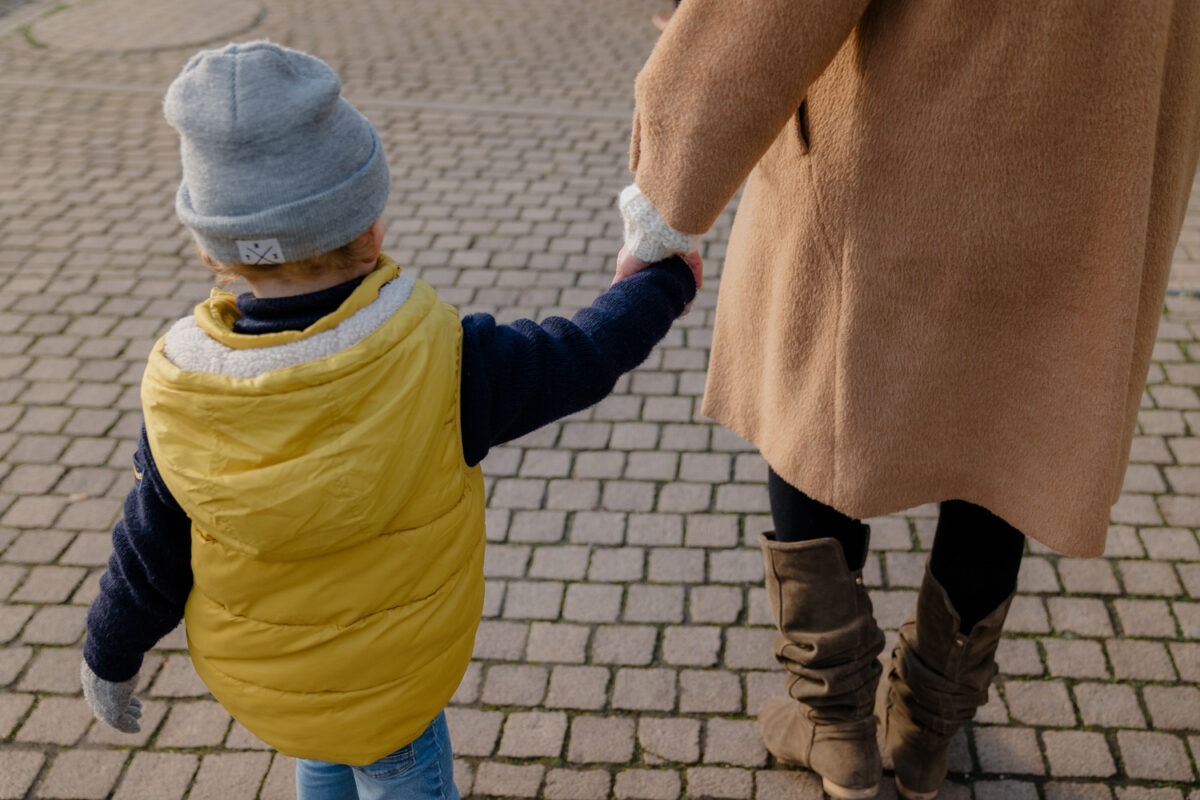 dokumentarische Aufnahme, Junge fasst Mutter beim laufen an die Hand