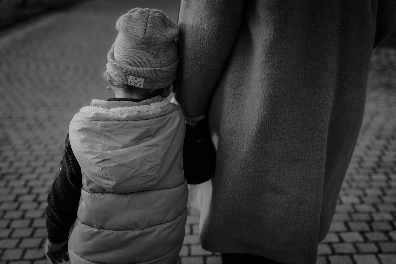 Schwarz-Weiss dokumentarische Aufnahme, Junge fasst Mutter beim laufen an die Hand