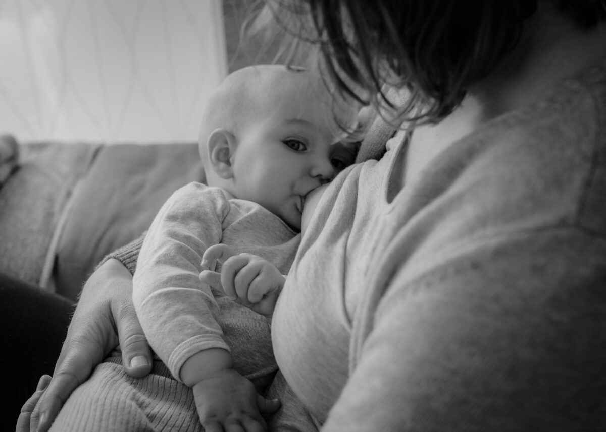 Warum Stillbilder? 2 Stillbilder, Schwarz-Weiss Stillfoto von Mutter mit Baby, Baby schaut in die Kamera während es trinkt