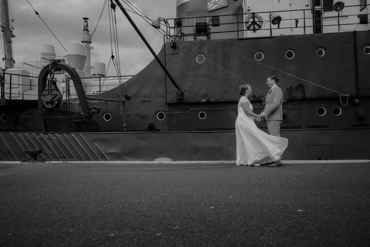 Schwarz-Weiß Aufnahme Braut mit wehendem Kleid vor großem Schiff im Fischereihafen Bremerhaven