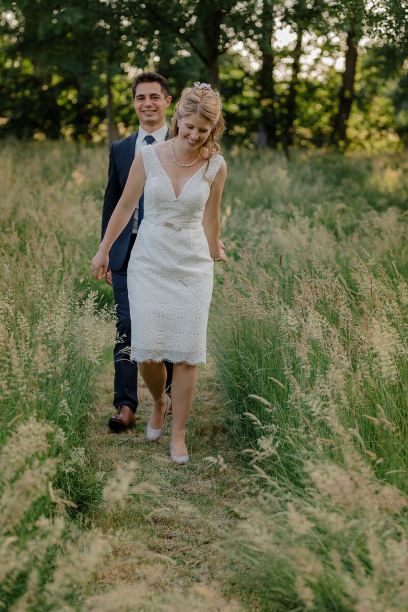 Hochzeits- und Familienfotografie, Brautpaar lachend und laufend auf Wiese auf dem Lür-Kropp Hof Oberneuland