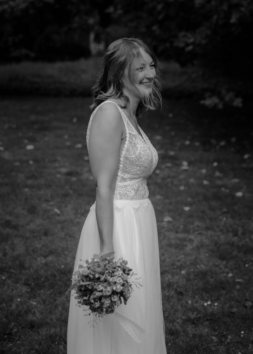 Schwarz-Weiss Aufnahme Braut mit Strauss, nach rechts schauend und lachend