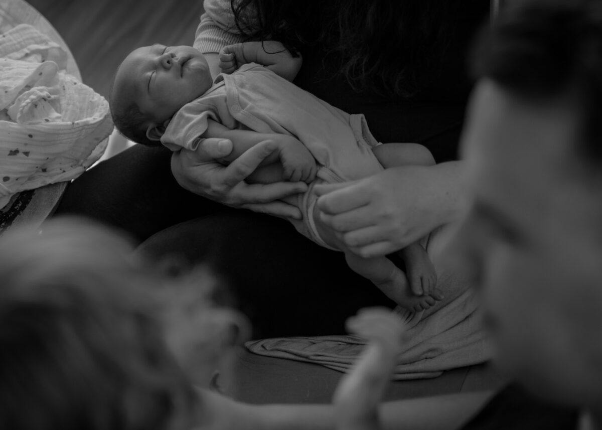 Was ist eine Wochenbettreportage? 2 Was ist eine Wochenbettreportage, Schwarz-Weiss Aufnahme von Familie mit Baby in der Mitte, Baby schläft