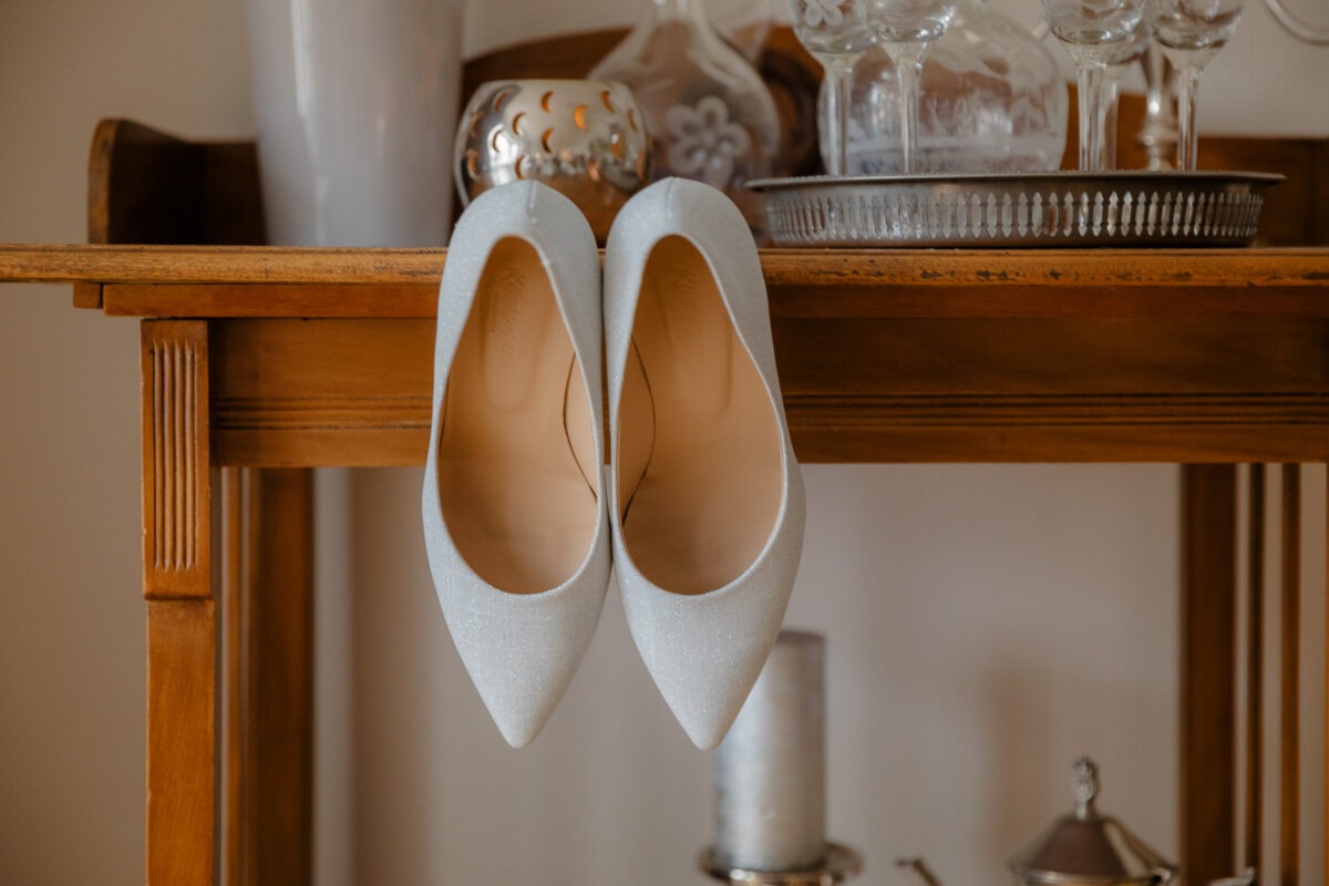 Brautschuhe hängend an Regal