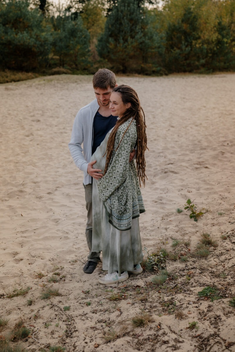 Schwangerschaftsfotografin in Bremen: Unvergessliche Momente festhalten 8 Paarfoto, Paar in den Dünen, Frau mit Babybauch, Mann hält Babybauch