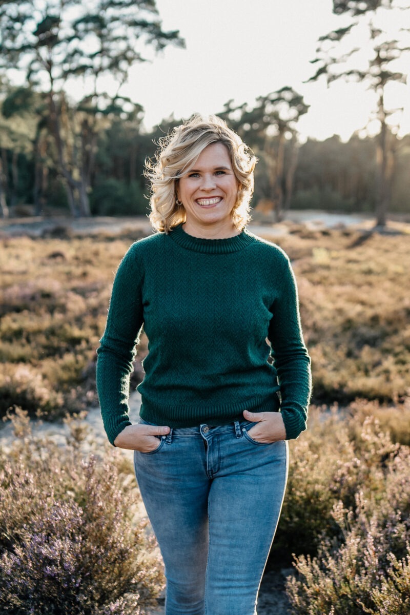 Ines, Hochzeitsfotografin aus Bremen, steht lächelnd in blühender Heide